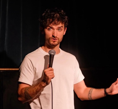 Callum Dibbert performing on stage with a microphone